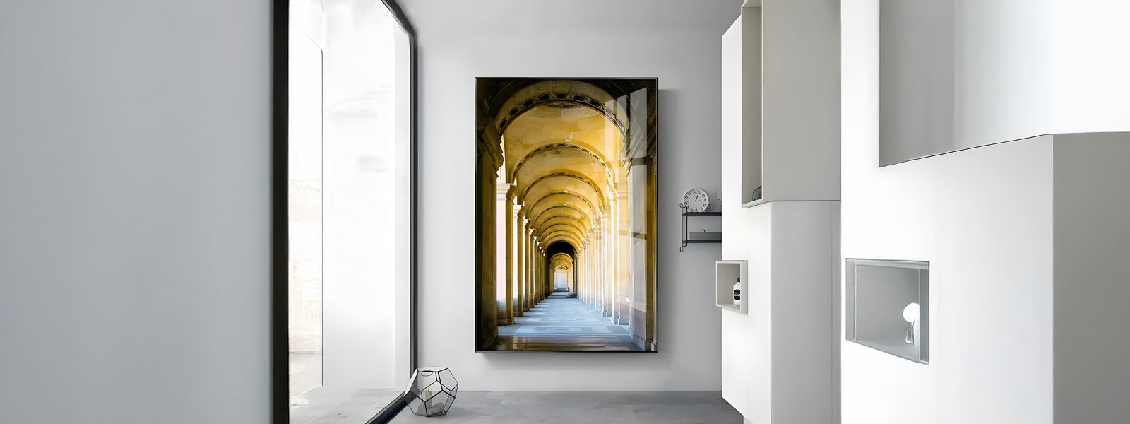 A modern room with a large framed picture of a yellow-lit archway on the wall. The interior features white walls, a clock, a hexagonal metal decor piece on the floor, and large windows.