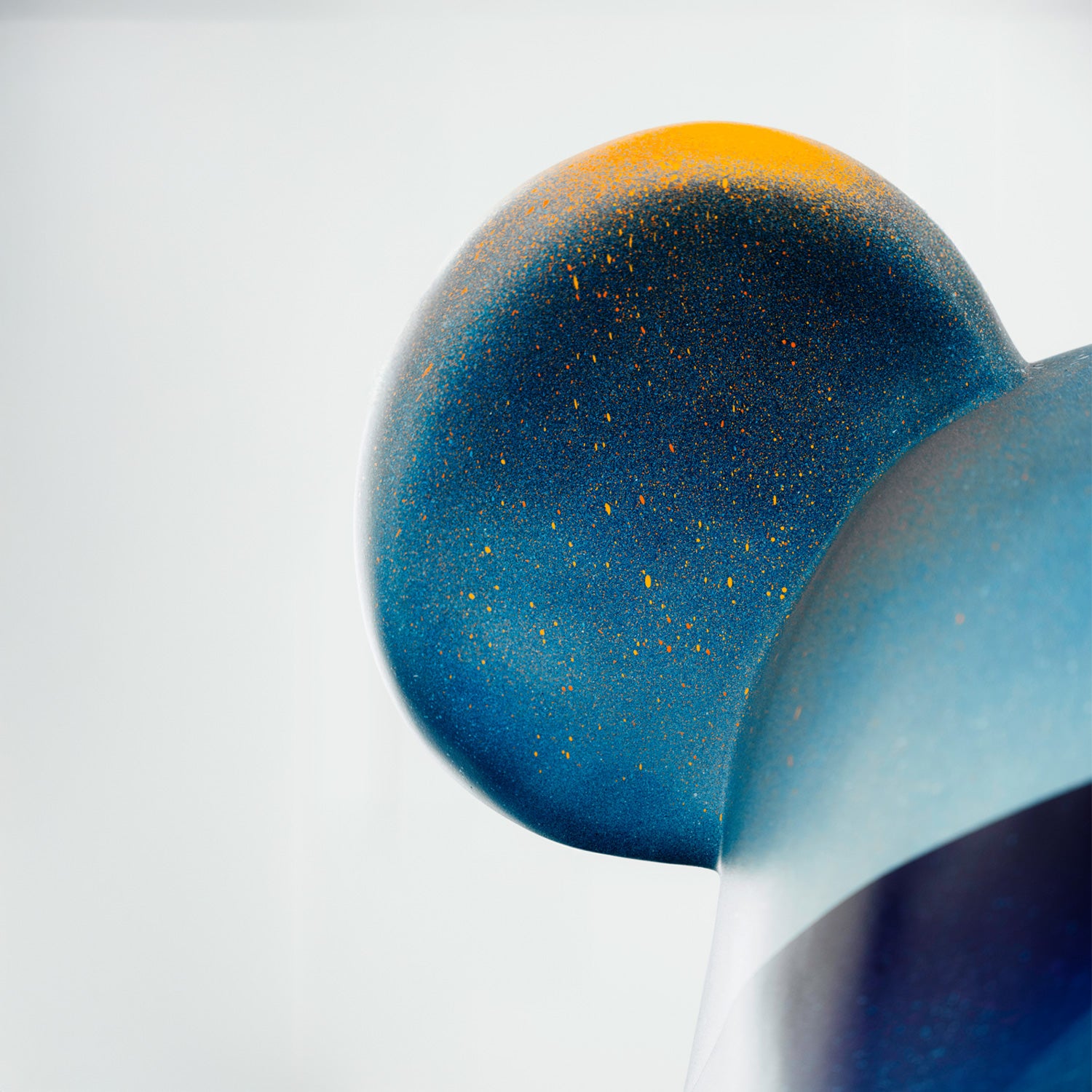 Close-up of the Giant Sculptures limited edition Midnight Sunset Bear Sculpture - 165cm by Adam Illes, featuring a blue bear with a large round ear. The surface is speckled with orange and yellow dots, adding texture and contrast against a plain white background.