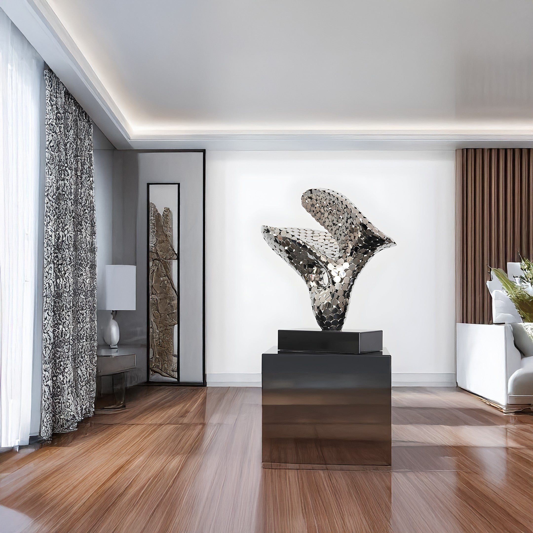 Silver sculpture displayed in a modern living room, positioned on a black stand.