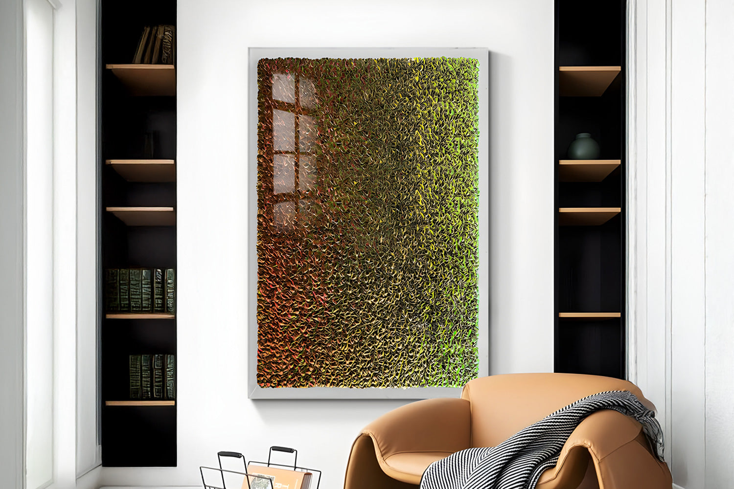 A modern room features a textured abstract painting with shades of green, brown, and gold. Adjacent are built-in shelves with books, a black vase, a tan leather chair, and a gray blanket. Ample natural light brightens the space.