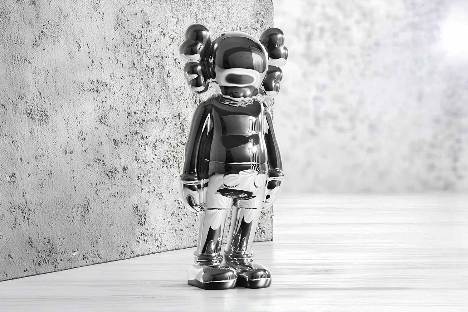 A reflective silver sculpture of a character with round ears and simple, abstract features stands against a textured gray wall. The floor and background are also gray, creating a minimalist and modern setting.