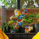 Pop art brightly colored gorilla sculpture with comic-style graphics, set against a window with green plants surrounding it.