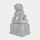 A substantial Chinese Guardian Lion V Marble Outdoor Sculpture by Giant Sculptures is positioned on an intricately carved pedestal. The mythical creature, reminiscent of a traditional Asian guardian lion, boasts a detailed mane and fierce expression. The background is plain white.