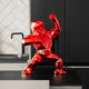 A vibrant red faceted gorilla sculpture with a reflective surface, positioned on a black countertop with a modern kitchen backdrop.