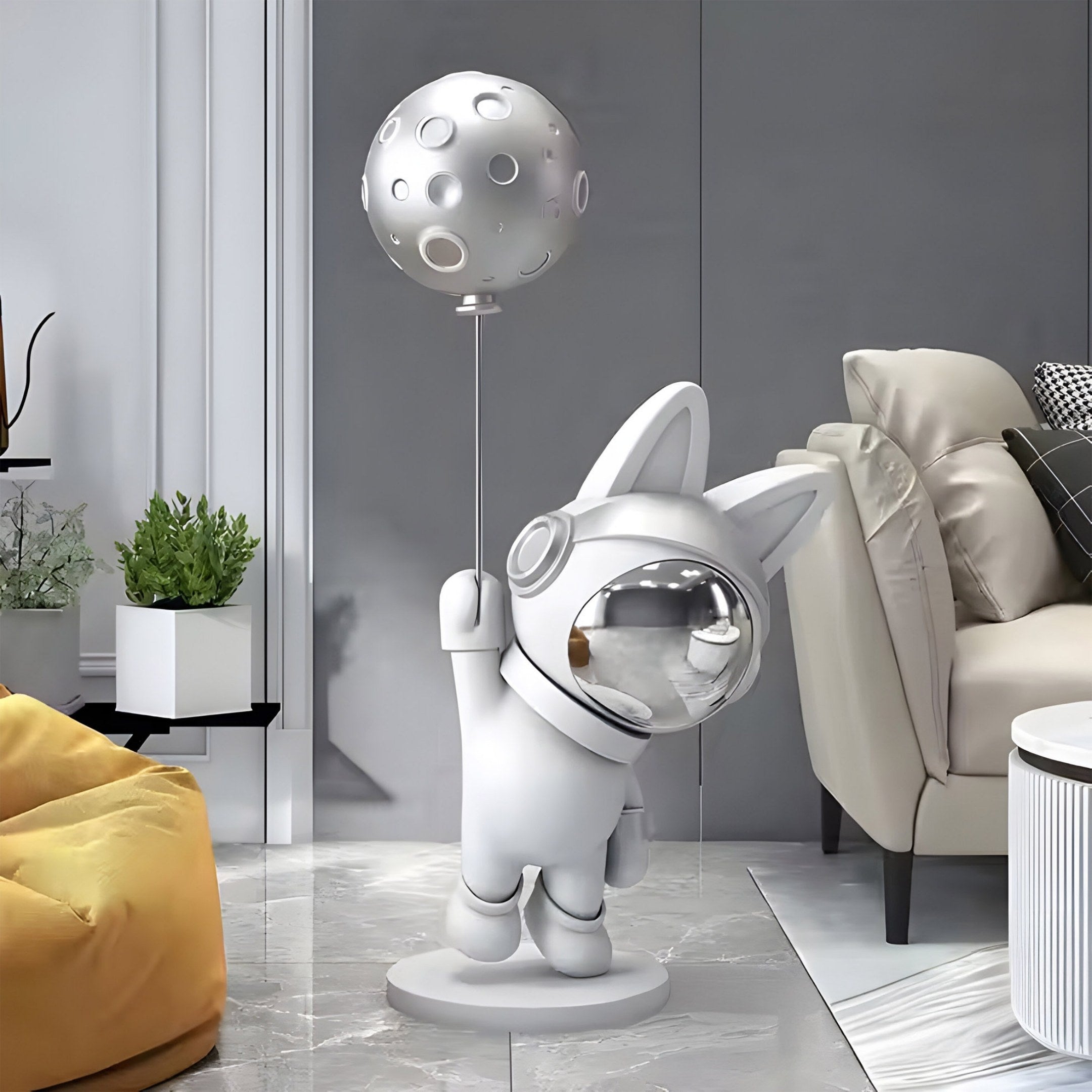 A modern living room showcases the Cosmic Chrome Astronaut Bunny Moon Balloon Sculpture (100cm) from Giant Sculptures. Its on a glossy floor near a beige sofa and green plant, complementing the space-themed décor, with a yellow beanbag to the left.