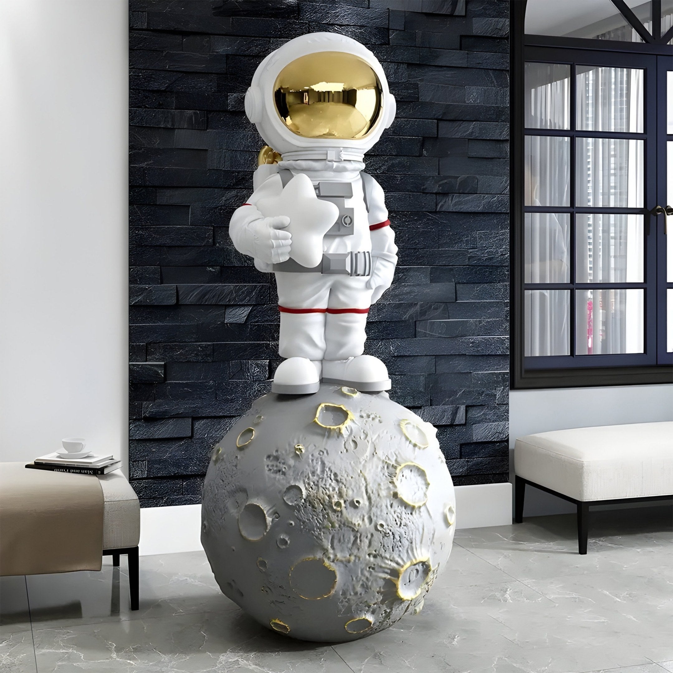 The Nova White Astronaut Star On Moon Sculpture by Giant Sculptures, at 125cm, shows a whimsical astronaut with a shiny gold helmet and thumbs-up gesture standing on a detailed cratered moon base, charmingly displayed against a textured black wall and partially opened window.