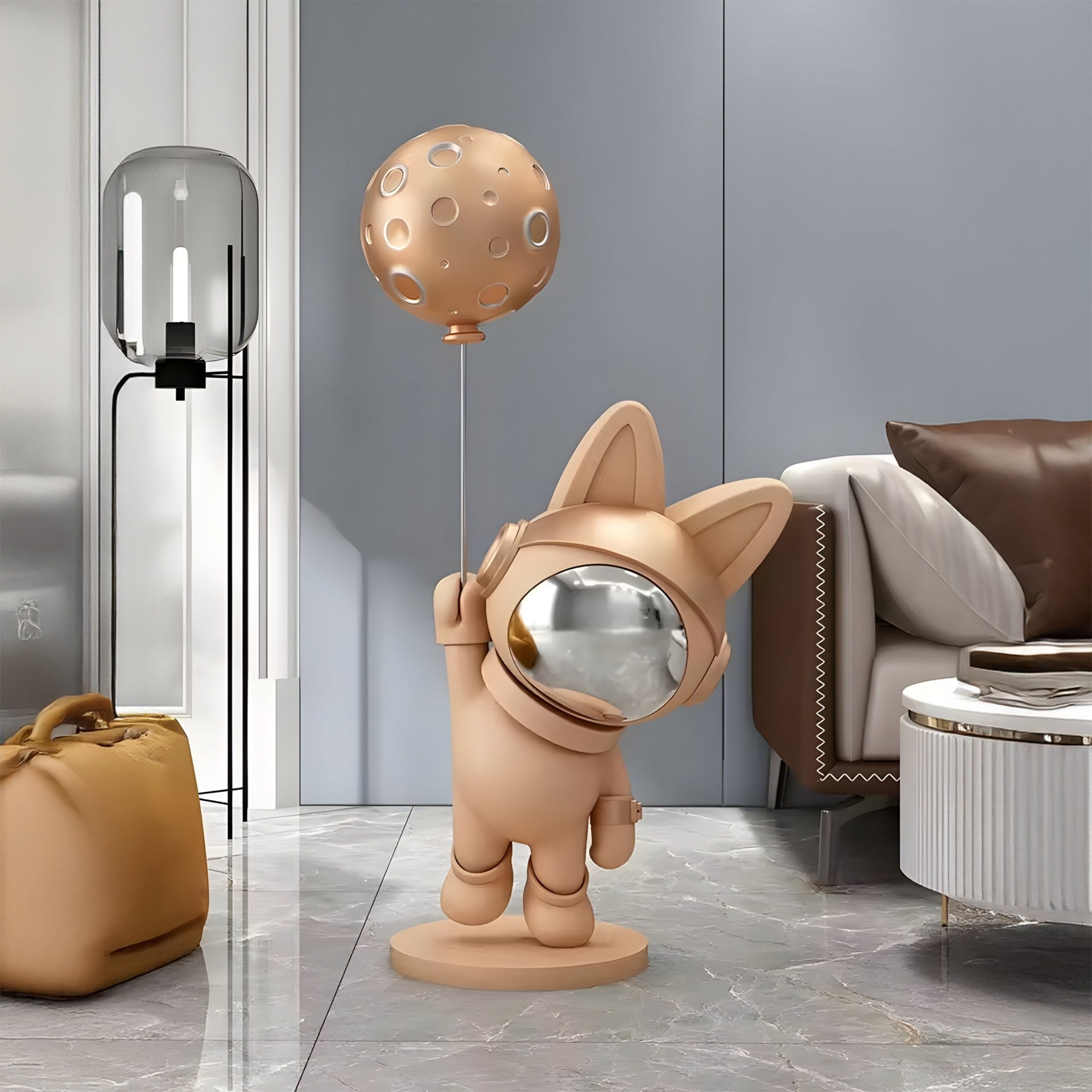 A modern living room features a Rose Gold Astronaut Bunny Moon Balloon Sculpture by Giant Sculptures, adding a cosmic touch. Perched on a marble floor, this scene is enhanced by a sleek lamp, taupe armchair, and small table.