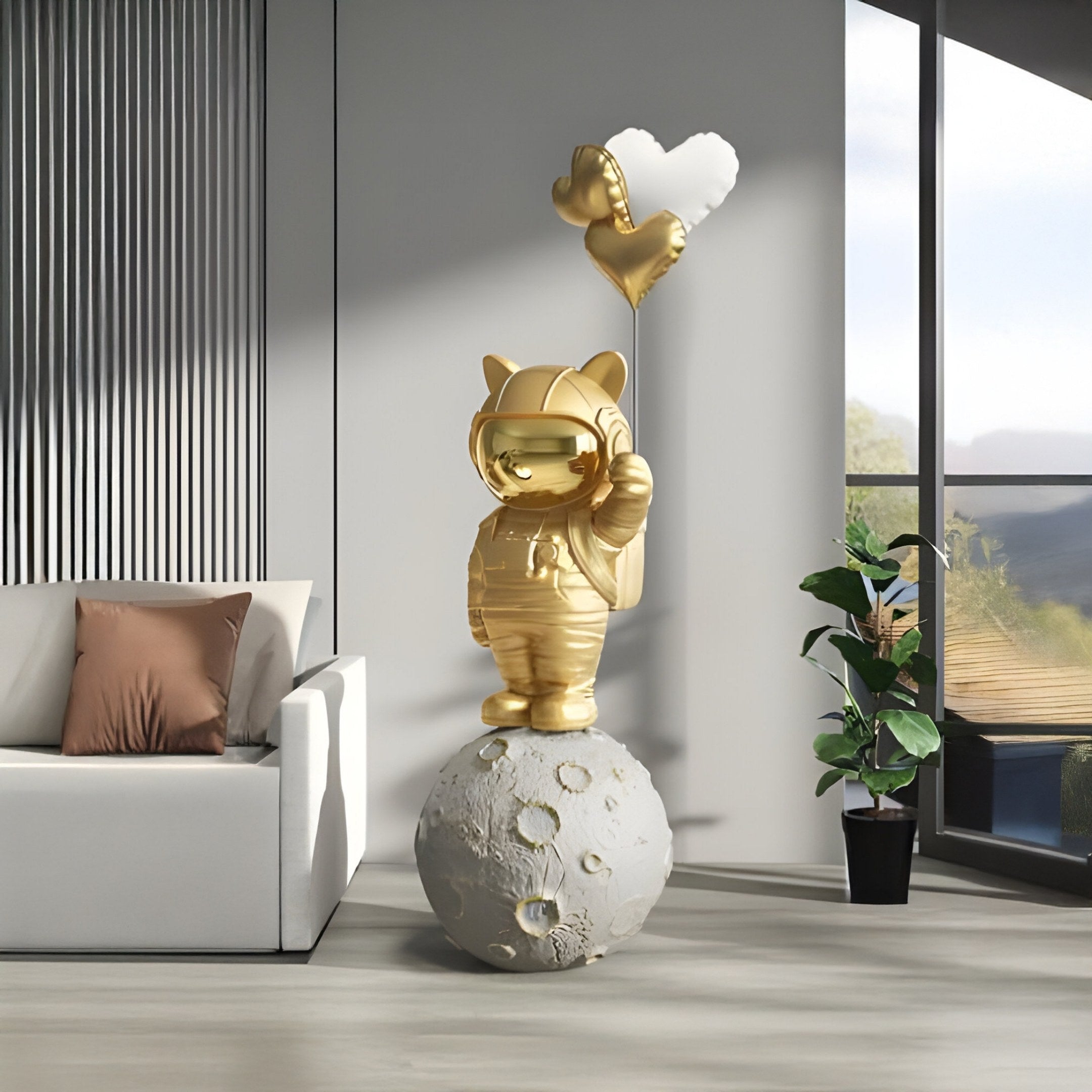 In a modern room with a white sofa, brown cushions, and a potted plant by tall windows, natural light creates serenity as the Gilded Gold Astronaut Kitty Heart Balloons Sculpture by Giant Sculptures stands on a lunar sphere holding silver heart-shaped balloons.