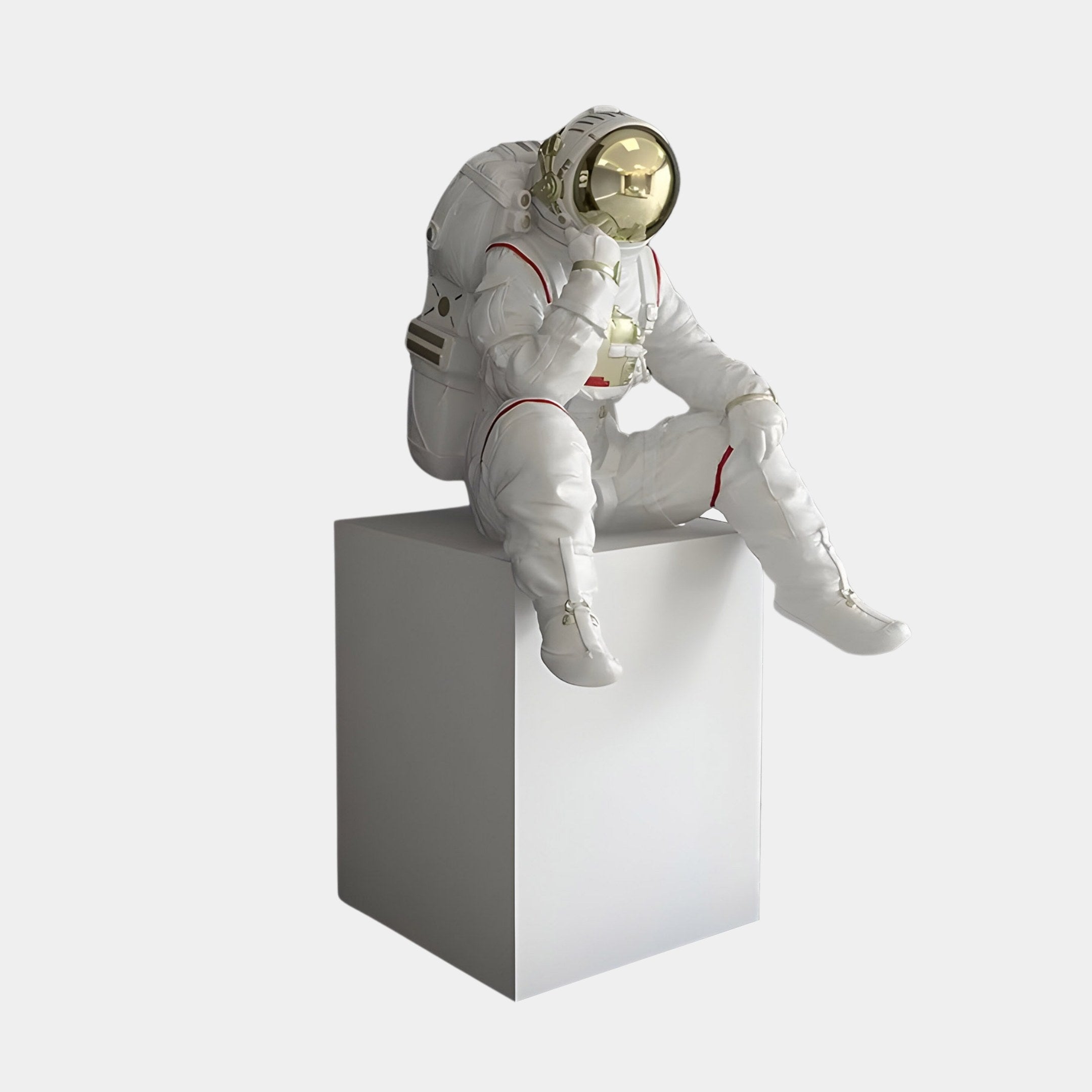 The Nova White Astronaut Thinker Sculpture by Giant Sculptures features a reflective astronaut in a white suit with a gold visor, seated pensively on a plain white cube against a light gray background. Standing at 65cm, its ideal for space-inspired decor.