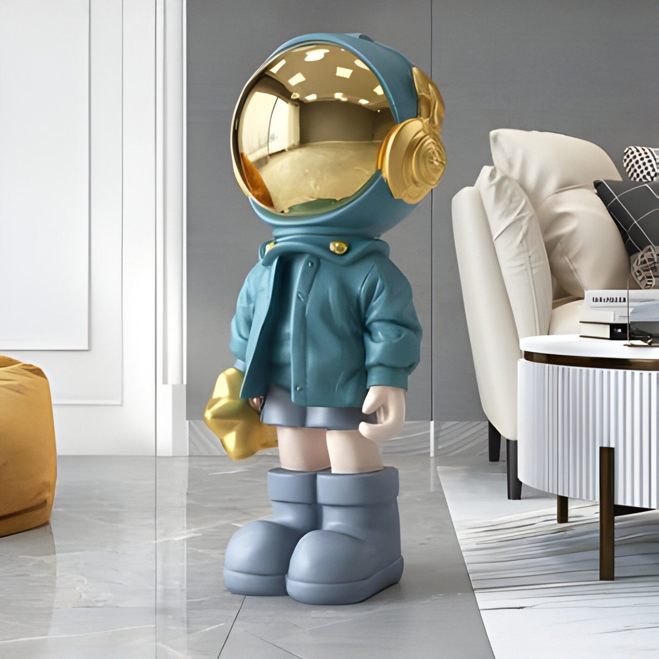 The Galactic Blue Astronaut Beats Sculpture by Giant Sculptures is a whimsical, 70cm space-inspired ornament featuring a figure with a gold helmet, oversized blue boots, headphones, and holding a gold item. It complements modern decor with items like a white table, beige armchair, and mustard ottoman nearby.