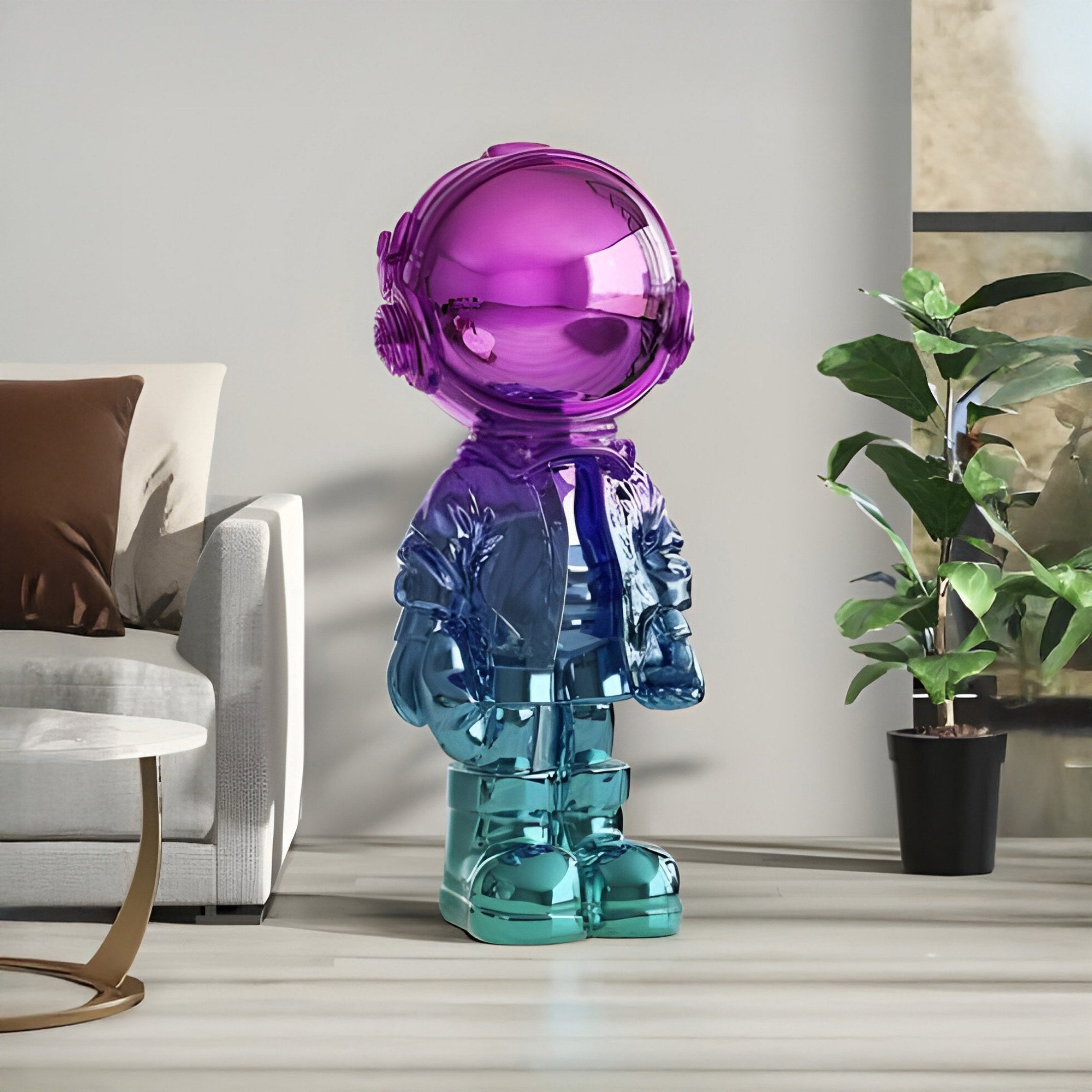 The Giant Sculptures Vibrant Gradient Astronaut Beats Sculpture (70cm) with hues of purple and blue is beside a white couch in a modern living room. A nearby plant and sunlight through the window cast enchanting reflections on its glossy surface.