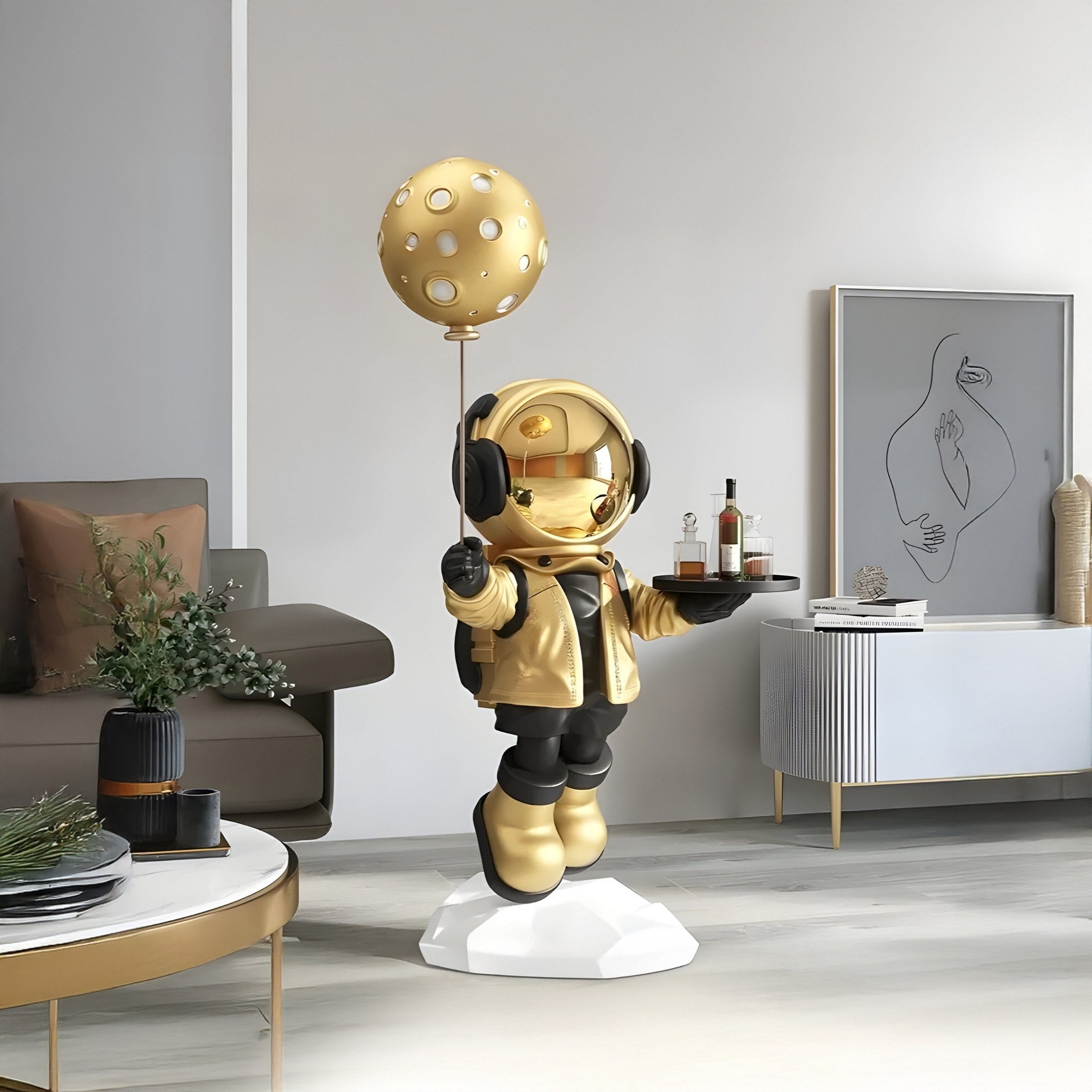 The Celestial Gold Astronaut Butler Balloon Sculpture by Giant Sculptures is an 80cm figurine featuring a whimsical astronaut with a moon-patterned balloon and drink tray, standing on a white base to complement modern, minimalist space-themed decor.