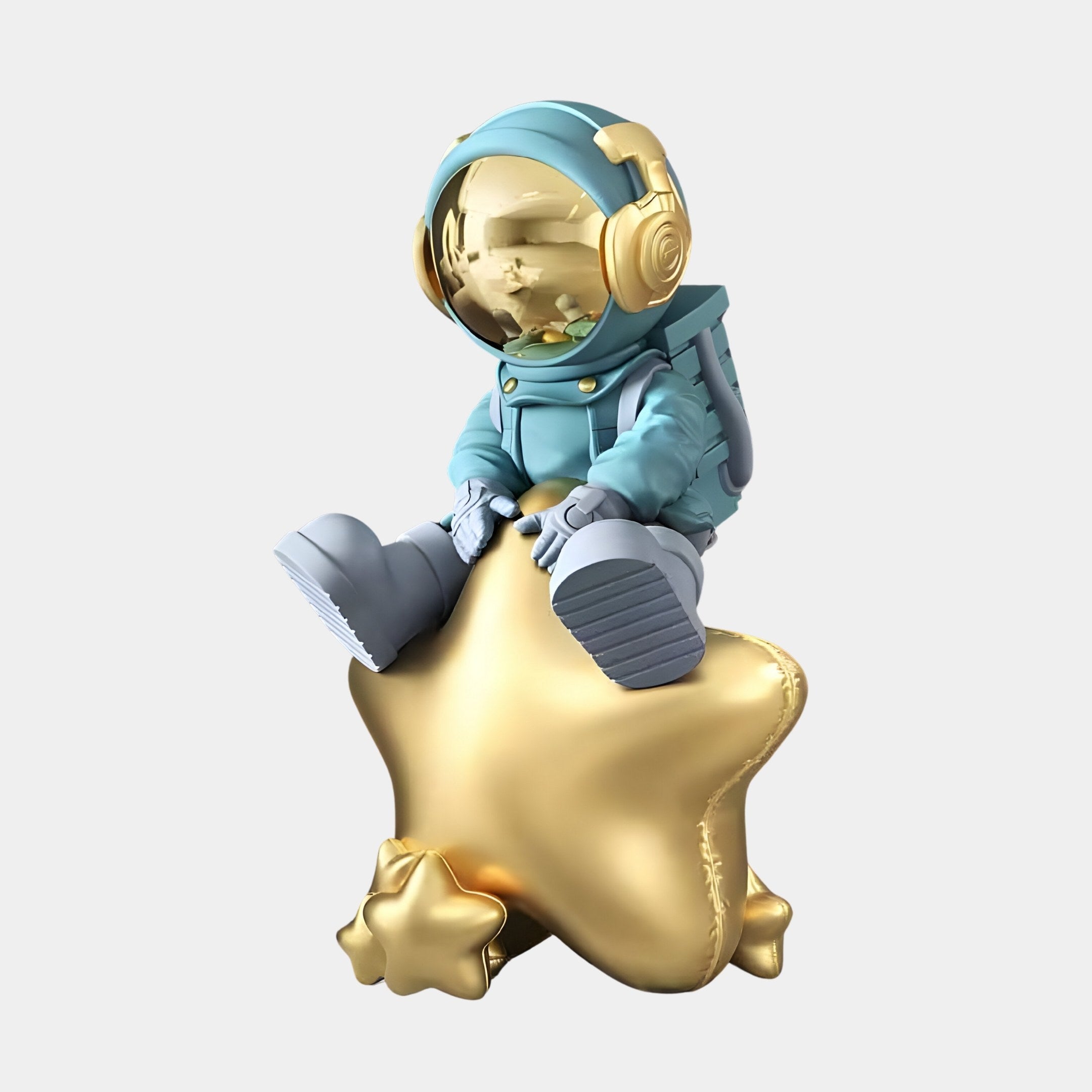 The Galactic Blue Astronaut Beats On Star Sculpture from Giant Sculptures features a whimsical child figurine in a galactic blue spacesuit with a gold visor, seated on a large golden star with hands resting on it, accompanied by a smaller star.