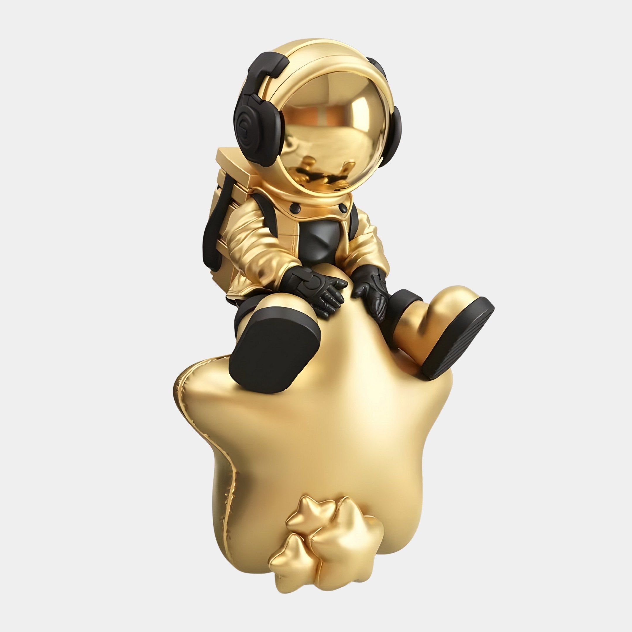 The Celestial Gold Astronaut Beats On Star Sculpture by Giant Sculptures is a 90cm golden figurine featuring black gloves and boots, large headphones, and sits on a star. The plain white background enhances its star-studded vibe with the small star at the base completing the décor.