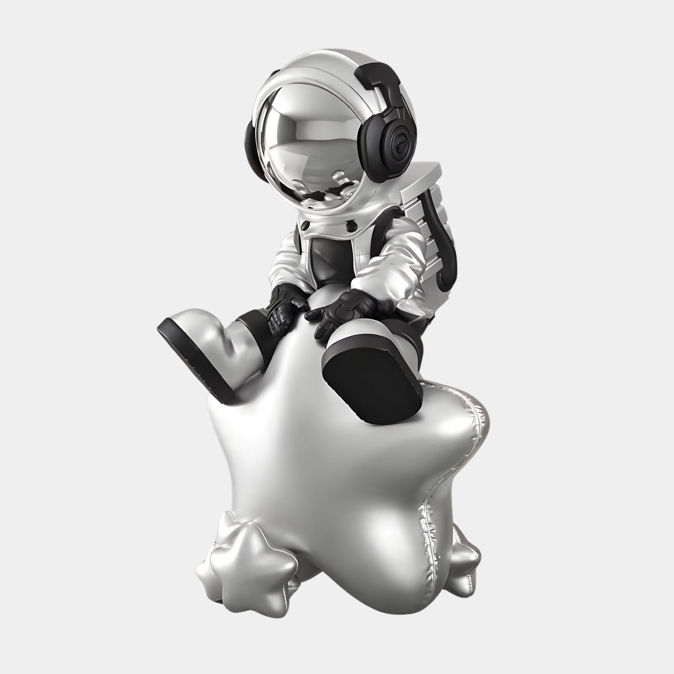 An Astral Silver Astronaut Beats On Star Sculpture by Giant Sculptures features a silver figurine with headphones on a star-shaped balloon, against a plain gray background.