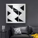 A modern living room showcases a sleek black leather sofa with a geometric black-and-white cushion. The Prismatics Black & White Geometric Cardboard Carving Wall Art by Giant Sculptures captivates above, while a small table to the left holds a sculpted face vase, completing the chic look.