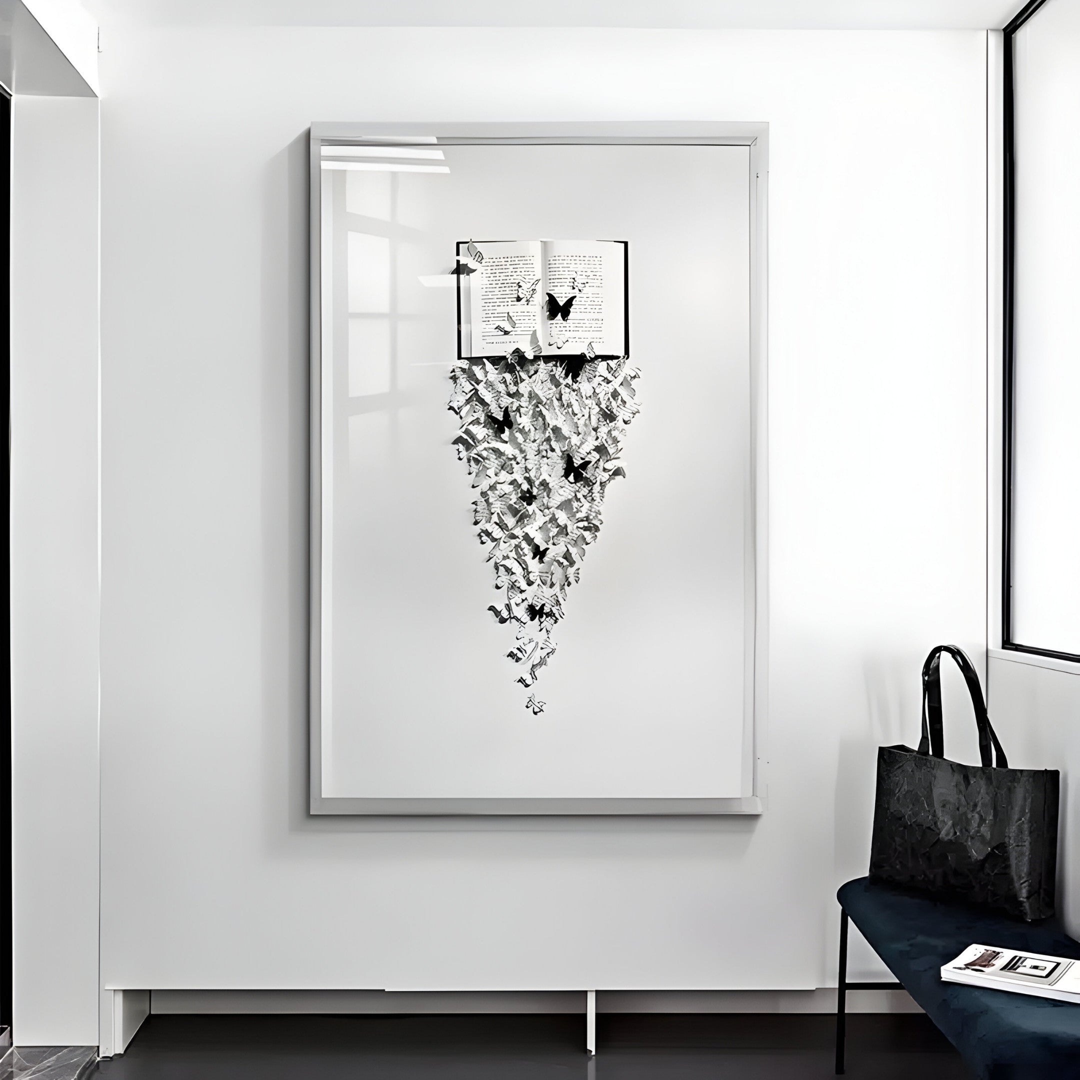 The Epiphany Black & White Butterfly Paper Wall Art by Giant Sculptures features an open book with pages transforming into butterflies. Nearby, a black bag sits on a bench, adding three-dimensional elegance to the bright, minimalistic room.