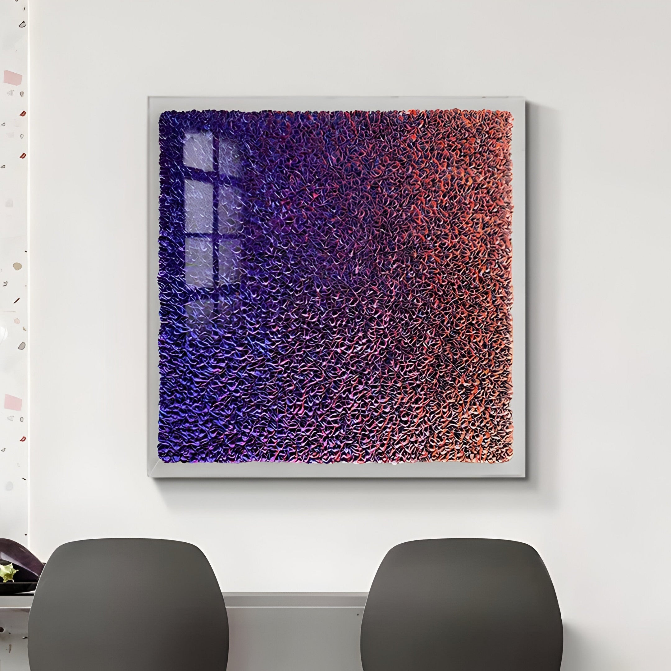 The Chromatica Square Vibrant Purple Gradient Paper 3D Wall Art by Giant Sculptures adorns a white wall. Two gray chairs sit below, with window pane shadows casting dynamic reflections on its textured blue and red layers.