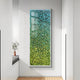 The Chromatica Rectangular Lush Green Gradient Paper 3D Wall Art by Giant Sculptures hangs on a white wall, combining textured blue and green hues. Sunlight casts shadows, while a small vase with white flowers rests on the nearby window seat.