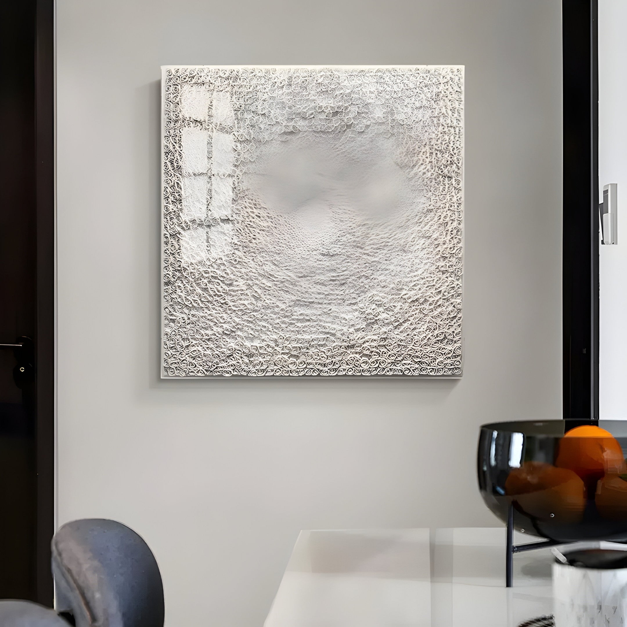 Displayed on a light gray wall is the TerraLuma Ivory White Bloom Paper Craft 3D Wall Art by Giant Sculptures. Beneath it, a sleek white table with a black glass bowl holding oranges is visible, creating a modern, minimalist ambiance.