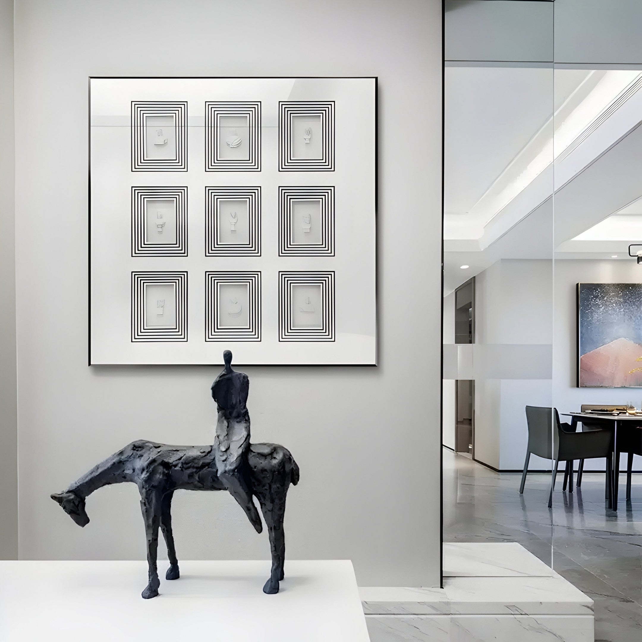 A modern interior features the Lustella Black & White Plaster Statue by Giant Sculptures on a marble surface. Hanging behind it is their Square Wall Art with nine geometric designs, while glass doors reveal a dining area decorated with a large black and white painting.