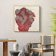 A modern room with a wooden chair and table is enhanced by Giant Sculptures Rosette I Wall Art, featuring a gold frame and vibrant red circular pattern. Decorative stones and a leafy plant add an organic touch to the minimalist decor.