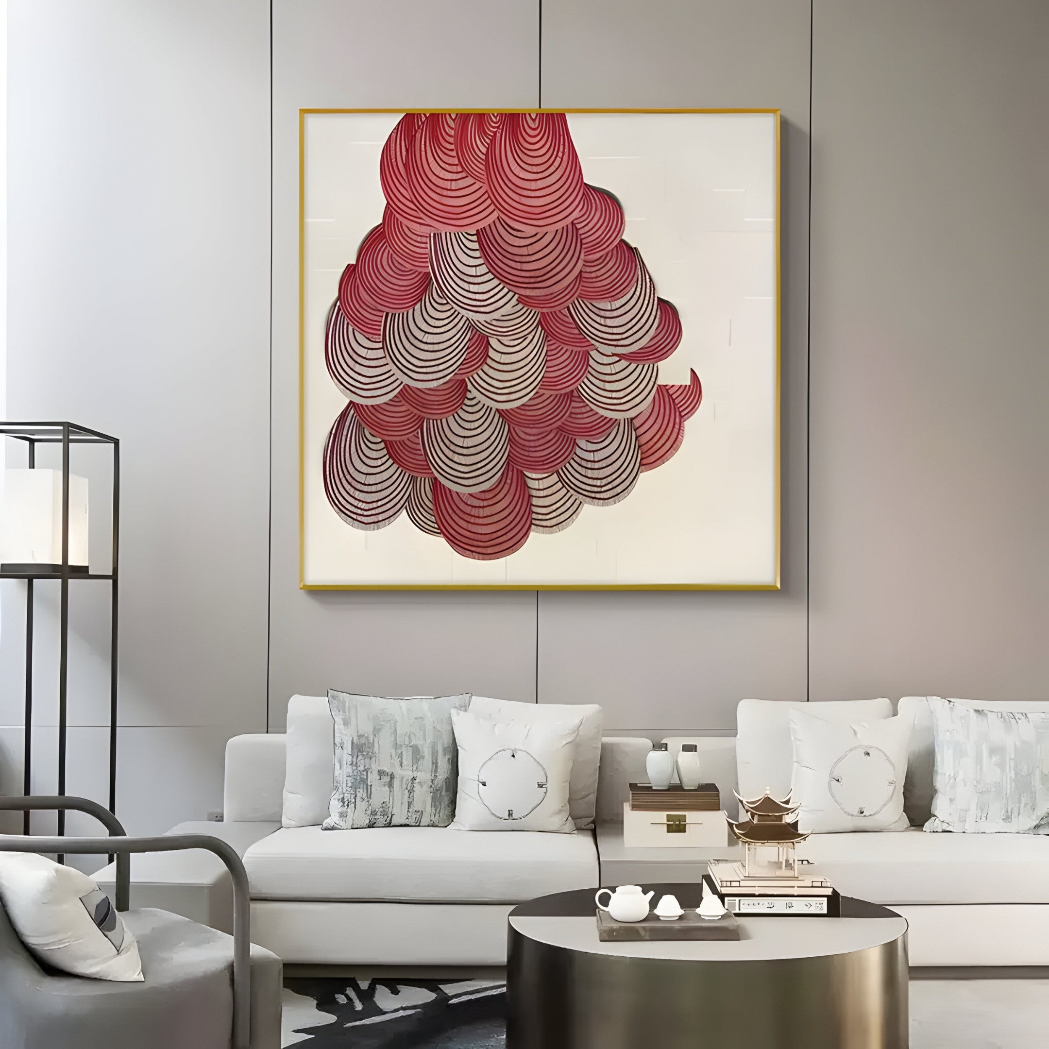 A modern living room boasts a neutral sofa with white and gray pillows, accompanied by a round black coffee table under a standing lamp. The space is enlivened by Giant Sculptures Rosette II Vibrant Red Circular Pattern Wall Art.