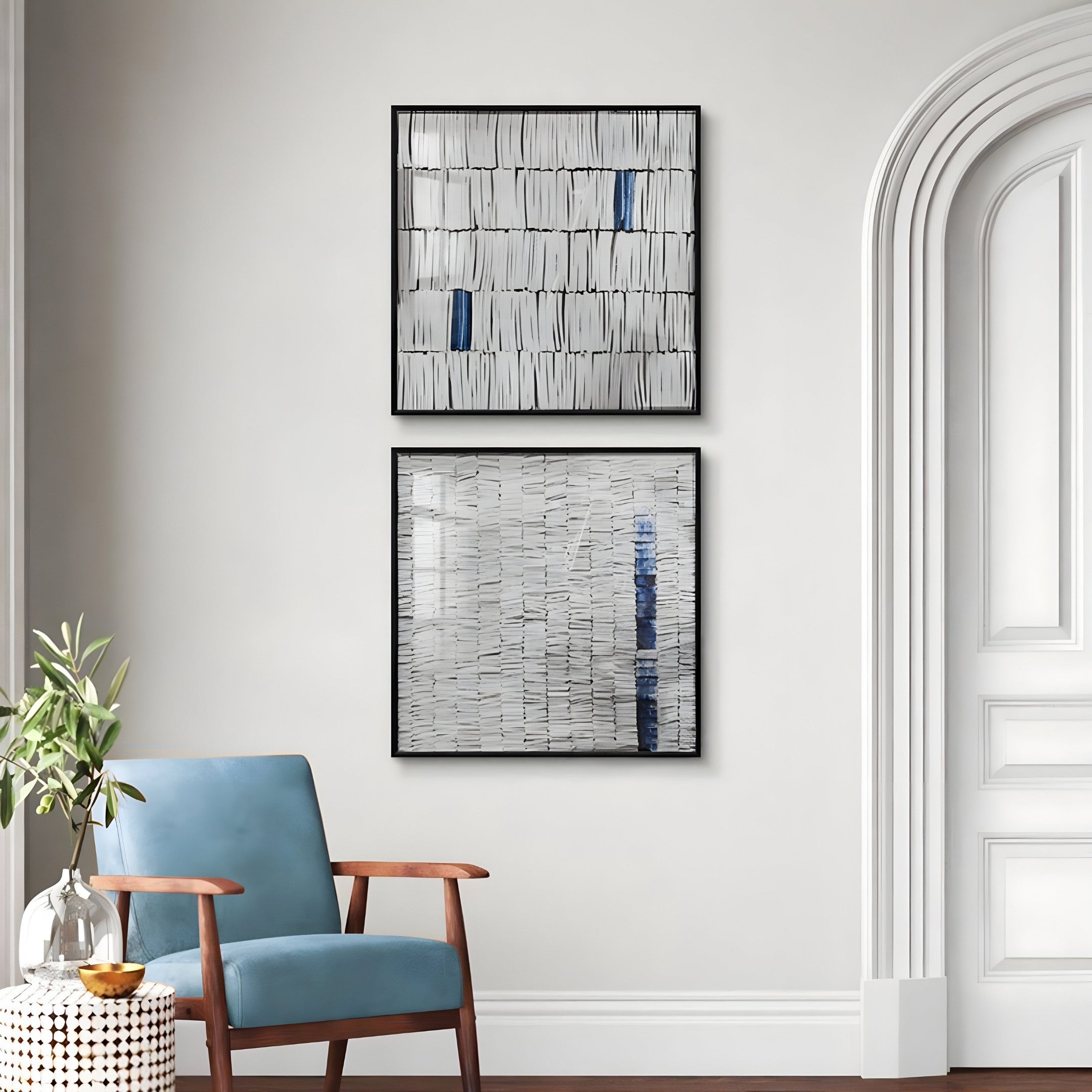 A minimalist room showcases a light blue armchair beside a small table with a plant. The light gray wall features two pieces of Giant Sculptures Tracery V Blue & White Textured Paper Wall Art, adding depth. The doors elegant molding details enhance the serene ambiance.