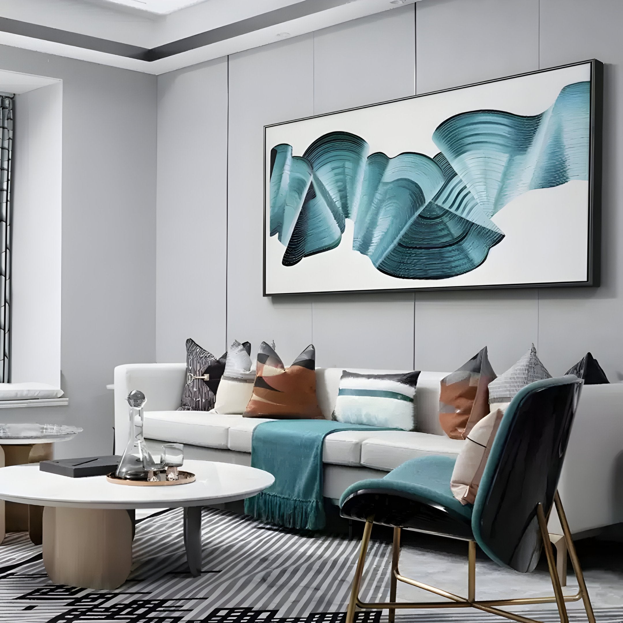 A modern living room showcases a white sofa adorned with cushions, a teal throw, and the Vortex Blue Spiral Silver Copper Wire Enamel Abstract Wall Art by Giant Sculptures. A sleek armchair and round coffee table with decor items enhance the style, while geometric rug patterns complete the look.