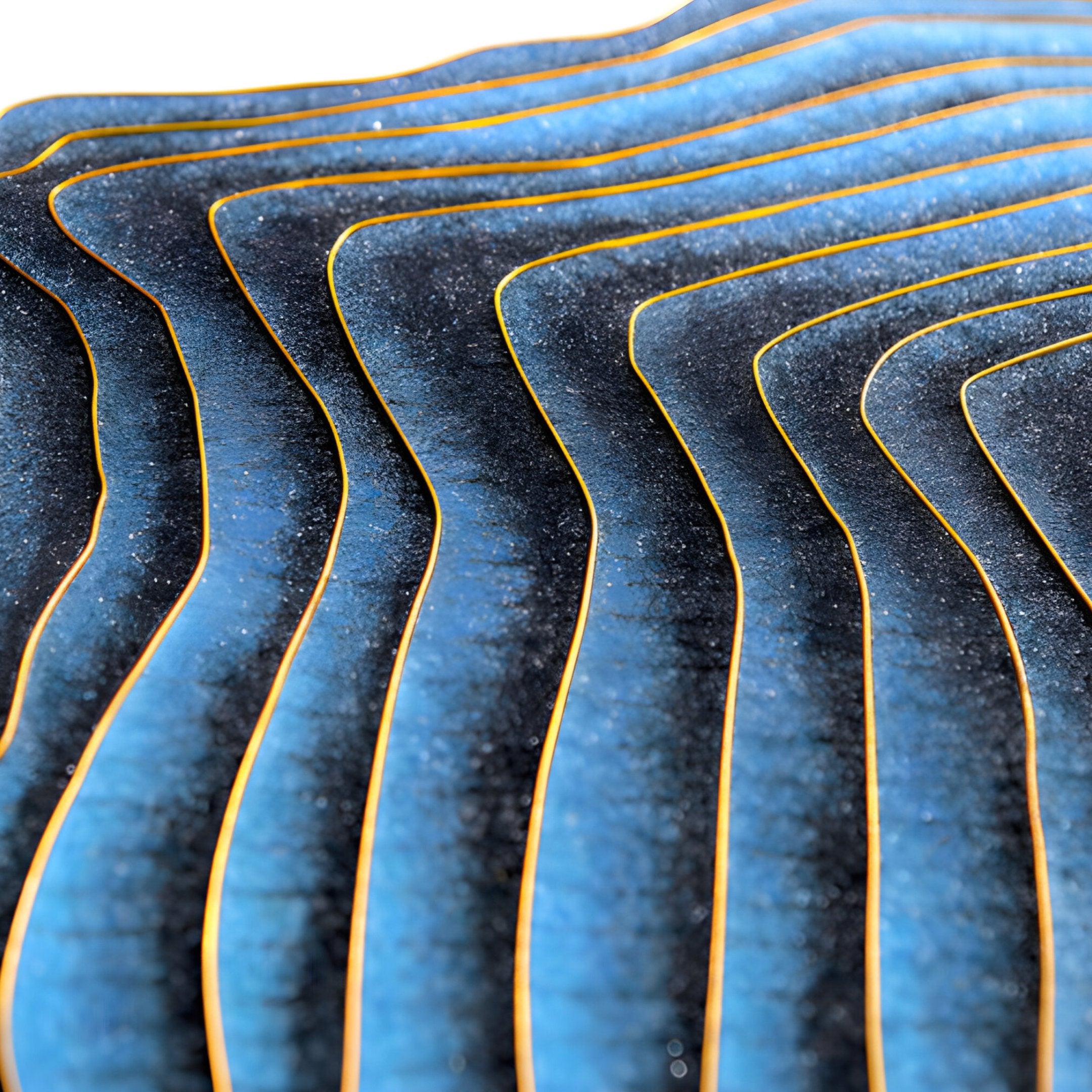 A close-up of the Auric I Blue Wave Abstract Copper Wire Enamel Round Wall Art by Giant Sculptures highlights its blue and black layers with golden edges, evocative of Zen Wall Art, featuring a smooth and glossy texture for a visually dynamic effect.