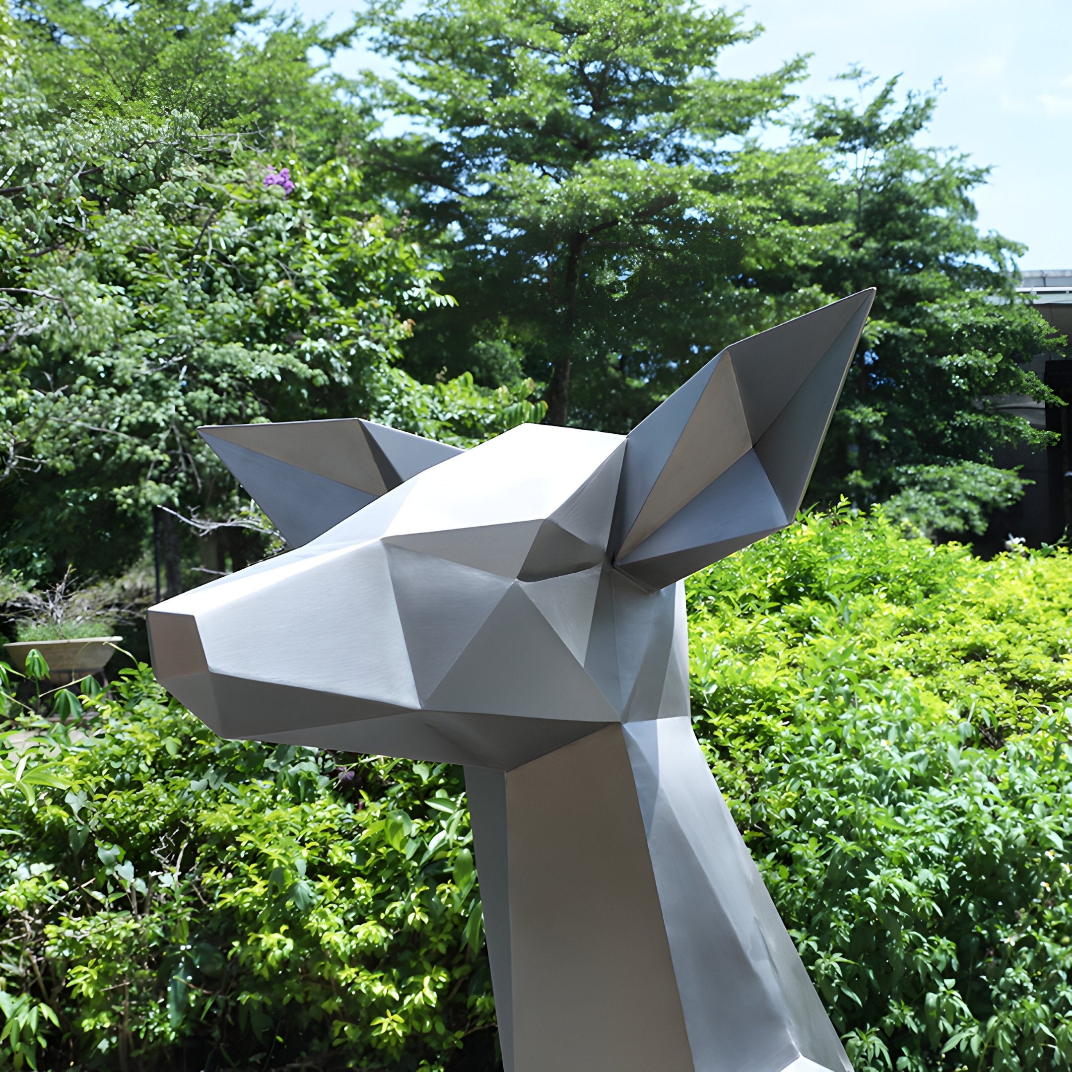 The Deer II Geometric Steel Outdoor Sculpture by Giant Sculptures stands elegantly as a 160cm modern art centerpiece in a lush green garden, with trees and a bright, clear sky forming the perfect backdrop.