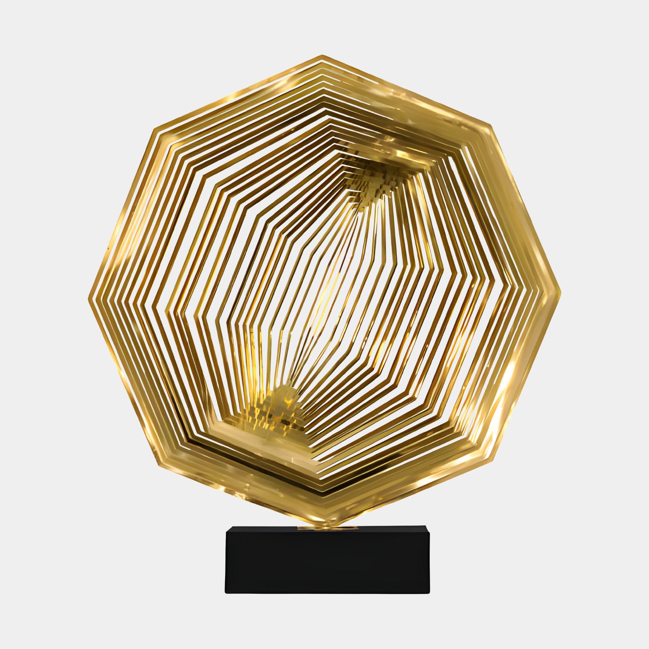 Golden hexagonal abstract sculpture with multiple thin layers of metal forming a geometric design, displayed on a black base.