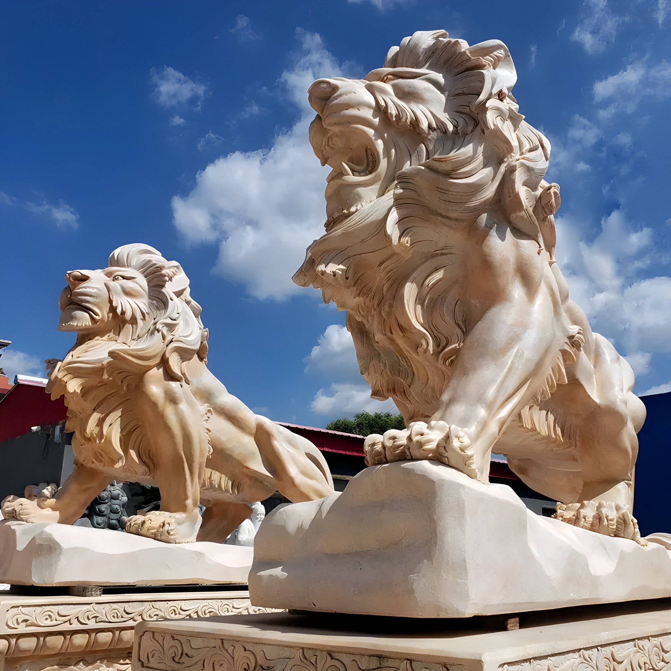 Set against a clear blue sky, the Giant Lion Yellow Marble Outdoor Sculptures from Giant Sculptures showcases two magnificent lion statues with fierce expressions. These customizable marble pieces are intricately detailed, capturing the lions in dynamic, roaring poses that exude power and artistry.