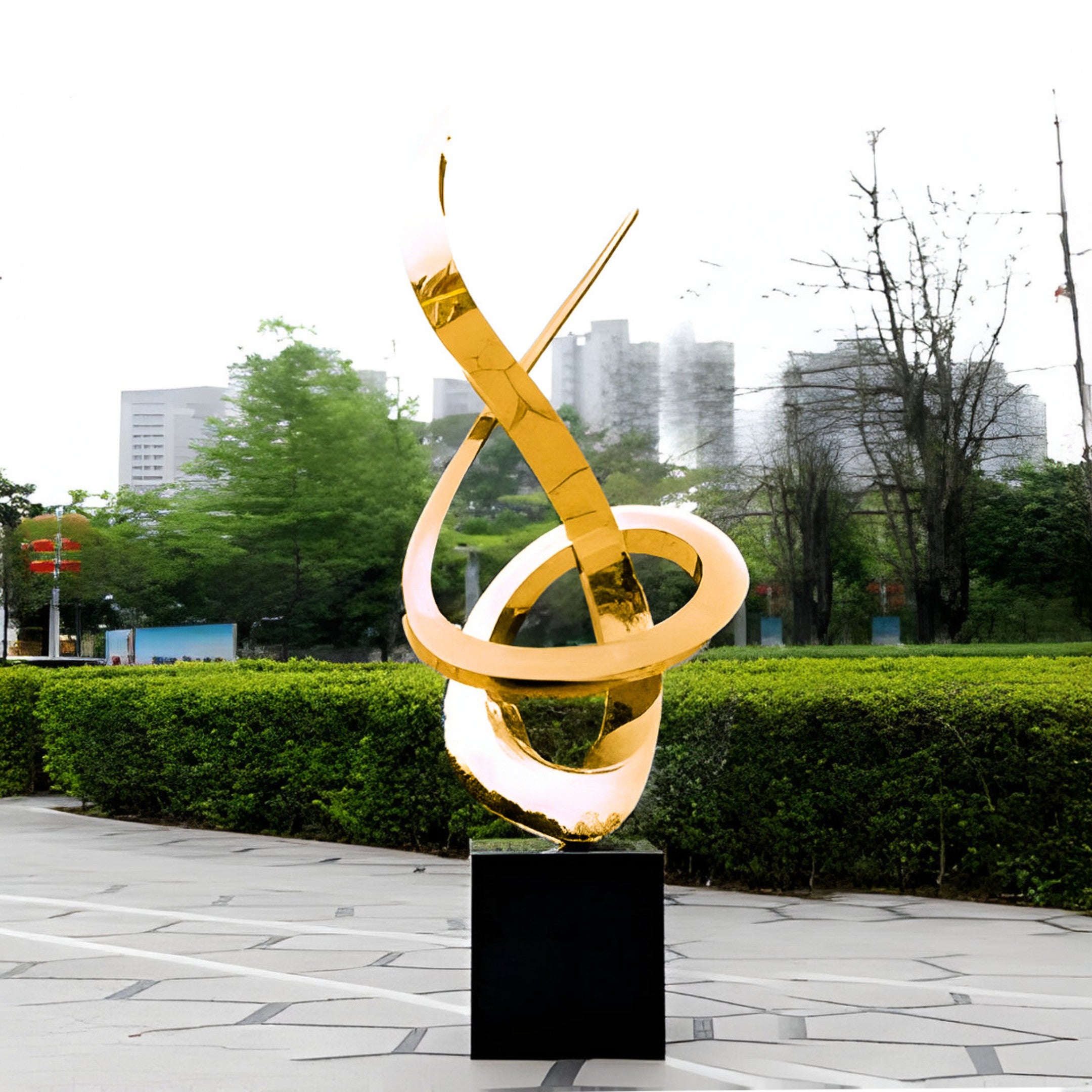 The gold sculpture displayed in an outdoor garden area.