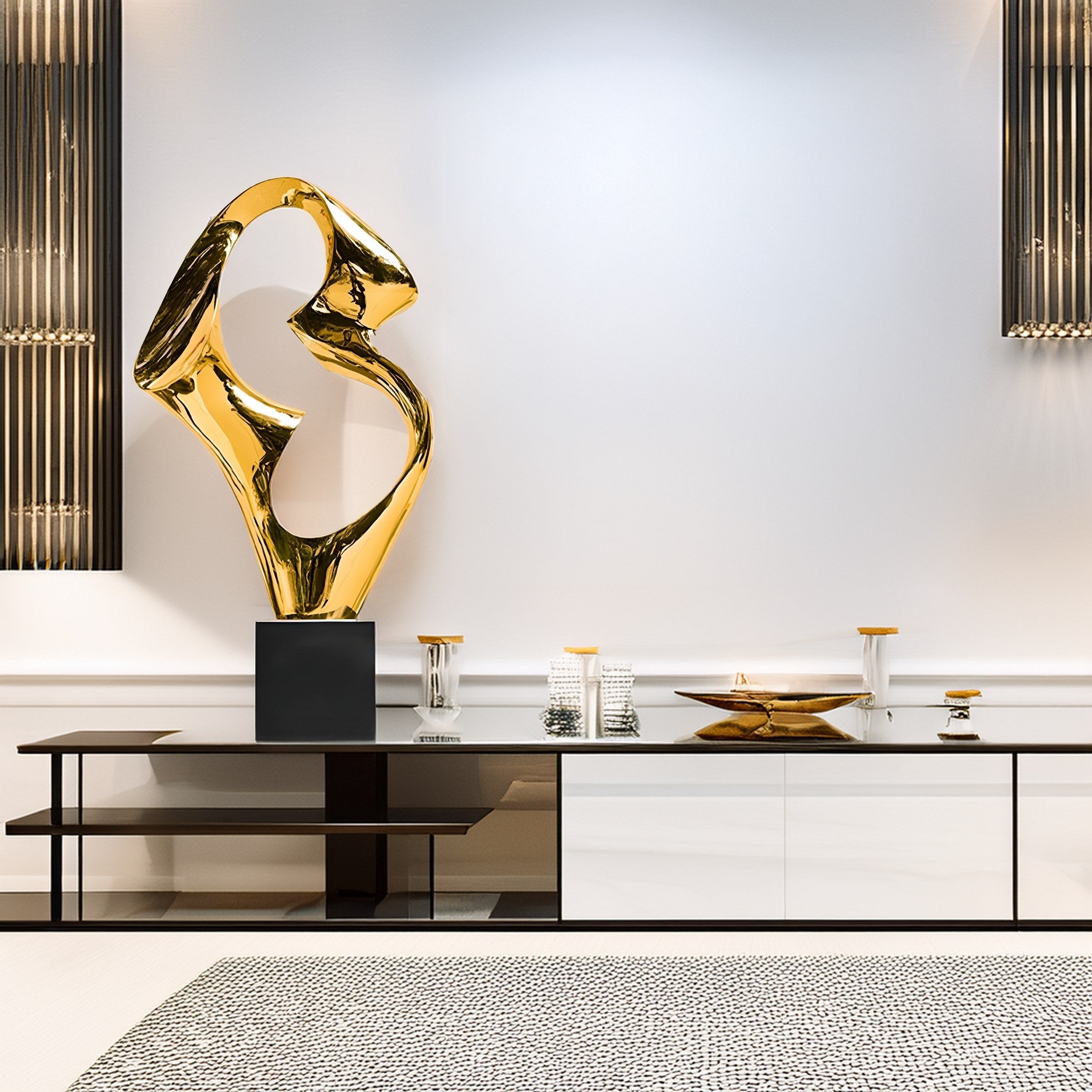 In a modern, minimalist room, the Flow III Gold Organic Steel Sculpture - 96cm by Giant Sculptures stands on a black pedestal. Sleek white cabinetry and textured gray carpet define the space, accompanied by ambient lighting and decorative items that enhance its organic design.