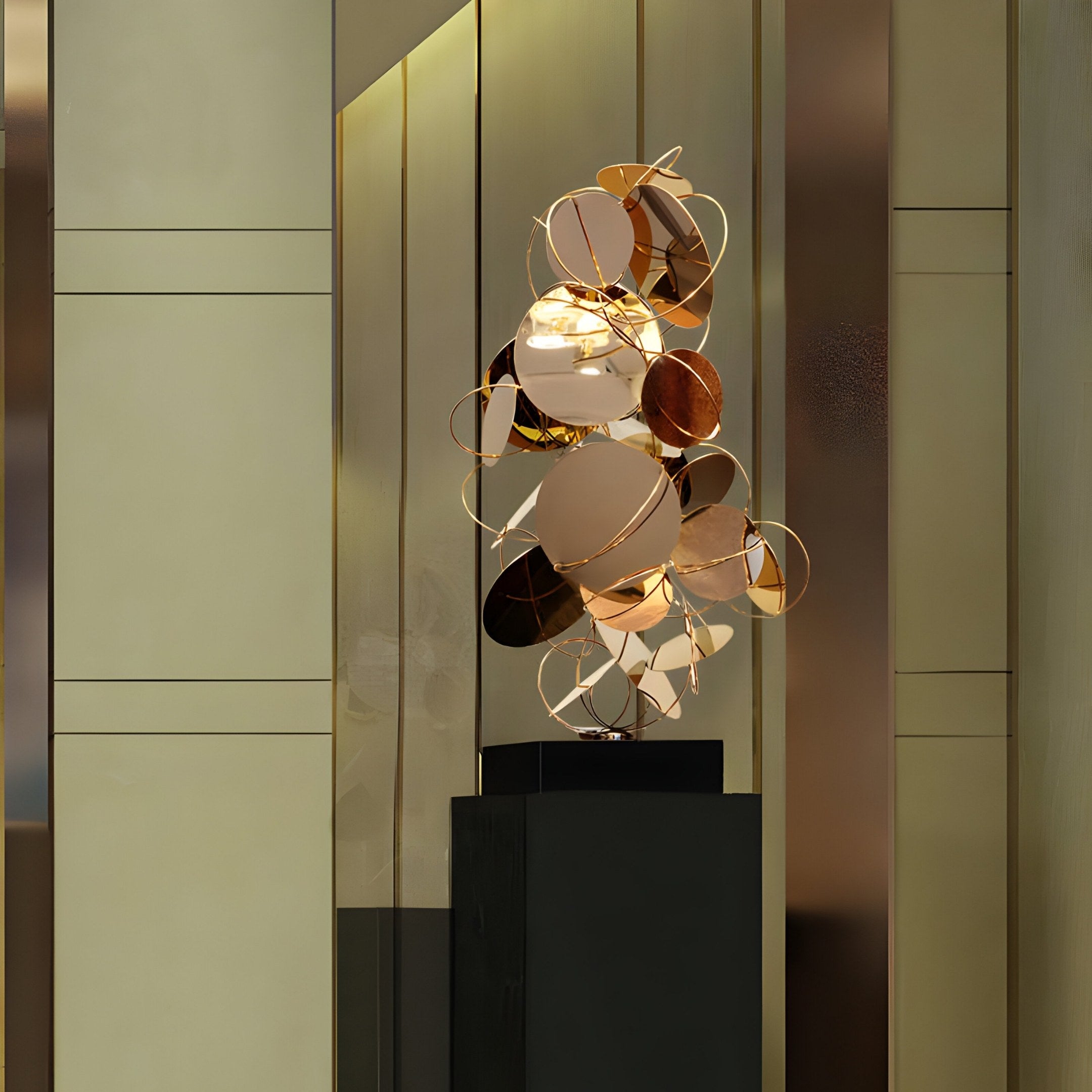 The Helios Copper Abstract Steel Sculpture (93cm) by Giant Sculptures, features interlocking gold and bronze shapes on a dark pedestal. Set against a reflective gold-toned wall, this stainless steel piece creates a luxurious ambiance.