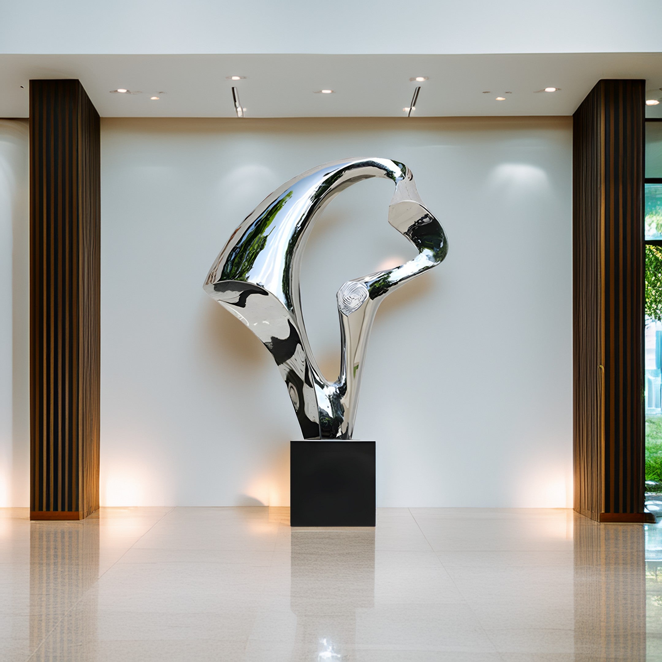 A silver abstract sculpture displayed in a contemporary lobby space, highlighting its metallic finish against a minimalistic backdrop.