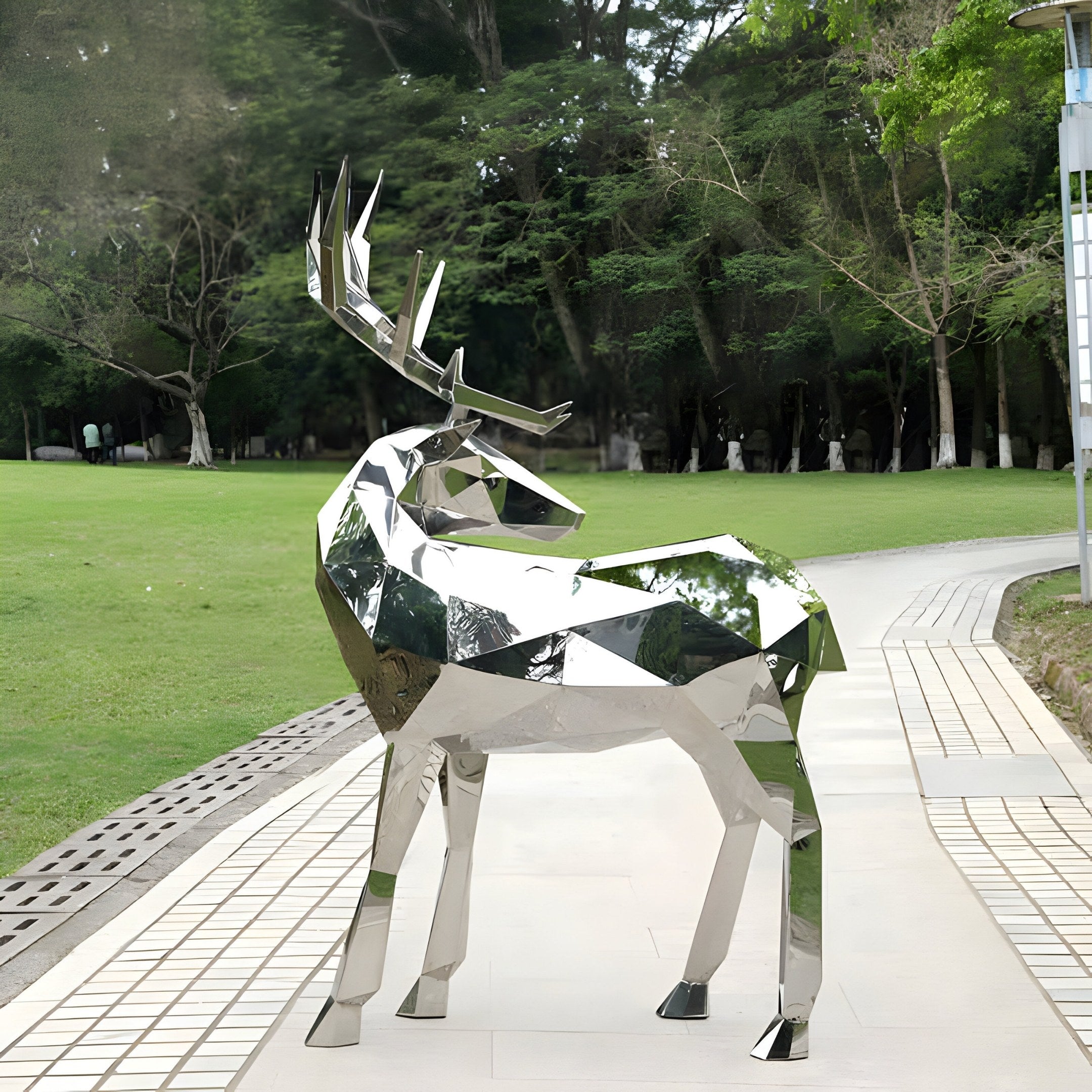 The Noble Deer Geometric Steel Sculpture (158cm) by Giant Sculptures shines on a park walkway, surrounded by lush green grass and trees as a natural backdrop.