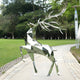 The Noble Deer II Geometric Steel Sculpture by Giant Sculptures, standing at 198cm, is a modern outdoor art piece. Made of stainless steel, it beautifully reflects green surroundings and graces the park pathway with its striking geometric design and large antlers.