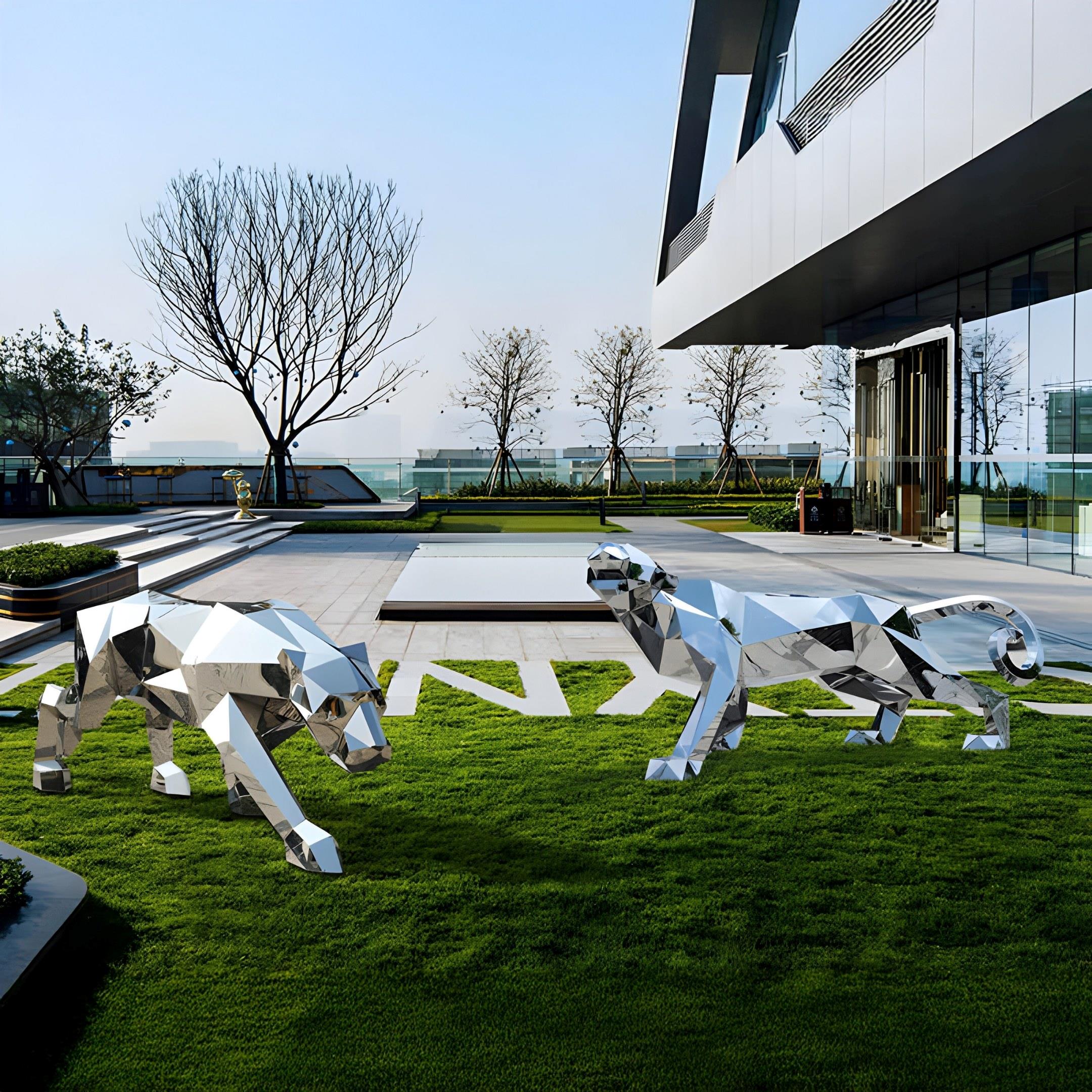 On a grassy courtyard outside a modern building, two Panther II Geometric Steel Outdoor Sculptures by Giant Sculptures stand majestically. At 217cm tall and crafted in stainless steel, they gleam under the clear sky, framed by leafless trees for a striking backdrop.