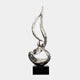 A tall, silver flame-like abstract sculpture on a black pedestal.