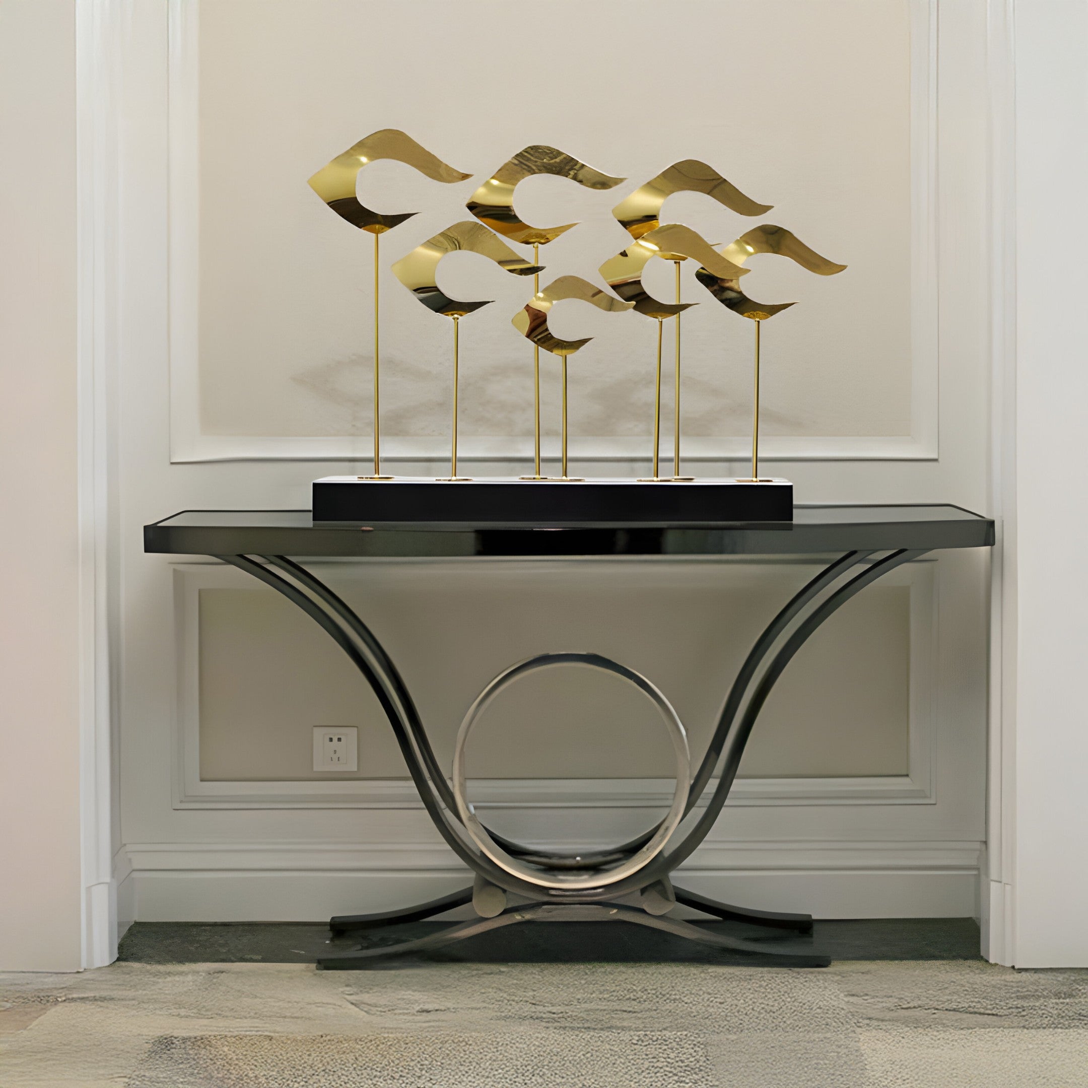 Gold wave sculptures styled in a modern home entryway, placed on a black and silver console table.