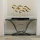 Gold wave sculptures styled in a modern home entryway, placed on a black and silver console table.