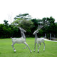 Two metallic deer sculptures with tree-branch antlers displayed in an outdoor garden, adding a natural yet modern touch to the landscape.