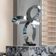 Infinity Loop stainless steel sculpture placed in a luxurious setting, with reflective surfaces interacting with the natural light to showcase its dynamic, abstract design.