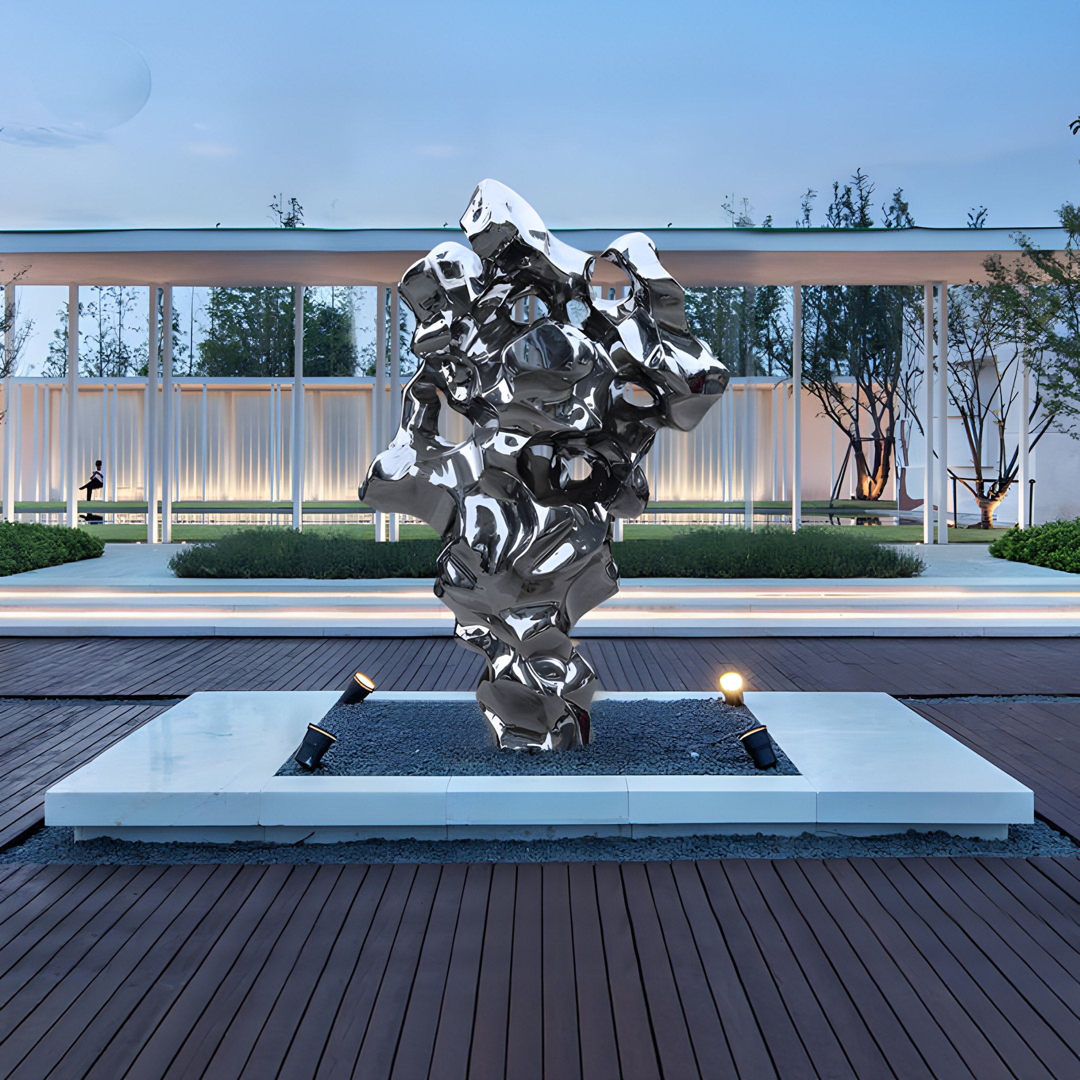 Reflective organic stainless steel artwork showcased in an outdoor garden. Modern decor centerpiece with abstract shapes, blending with natural surroundings.