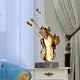 Gold violin sculpture placed on a bedside table in an elegant bedroom with soft blue furnishings.