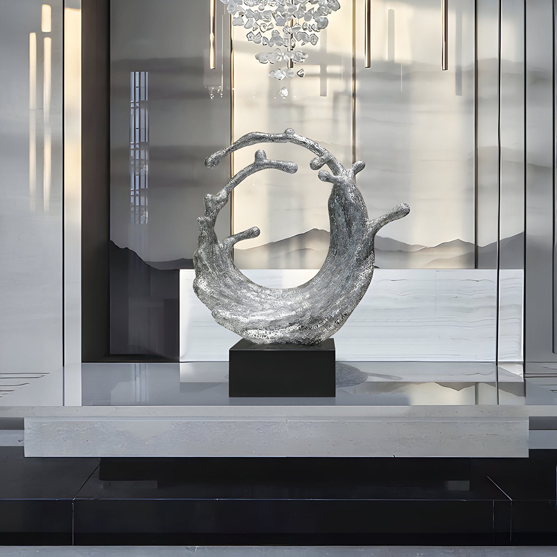 In an elegant interior adorned with mirrored walls and a chandelier overhead, the Timeless Wave Silver Organic Steel Sculpture by Giant Sculptures stands prominently on a pedestal. This 117cm modern sculpture captivates with its intricate circular design, casting dynamic reflections and shadows throughout the space.