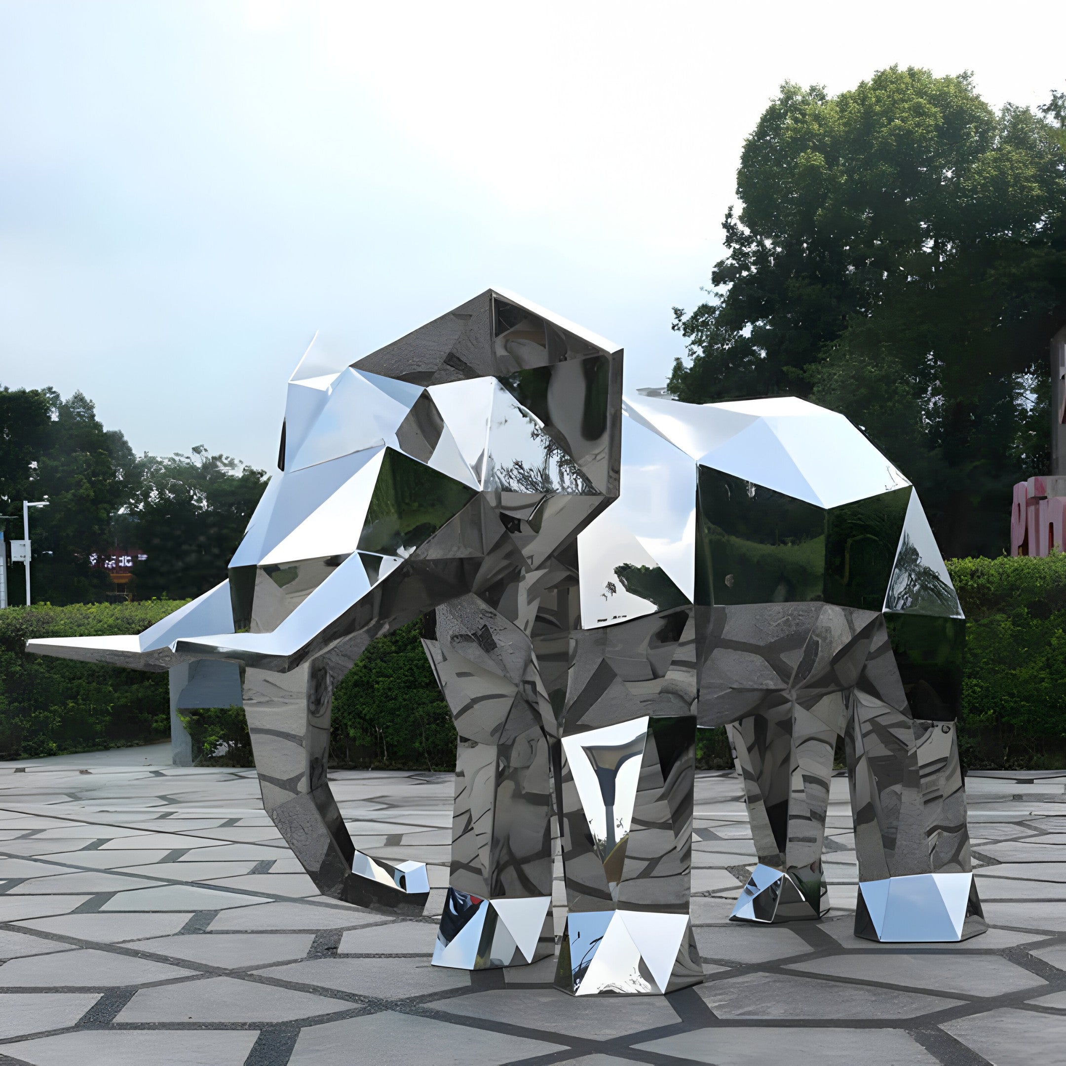 The elephant sculpture displayed outdoors on a modern plaza with reflections from nearby structures.