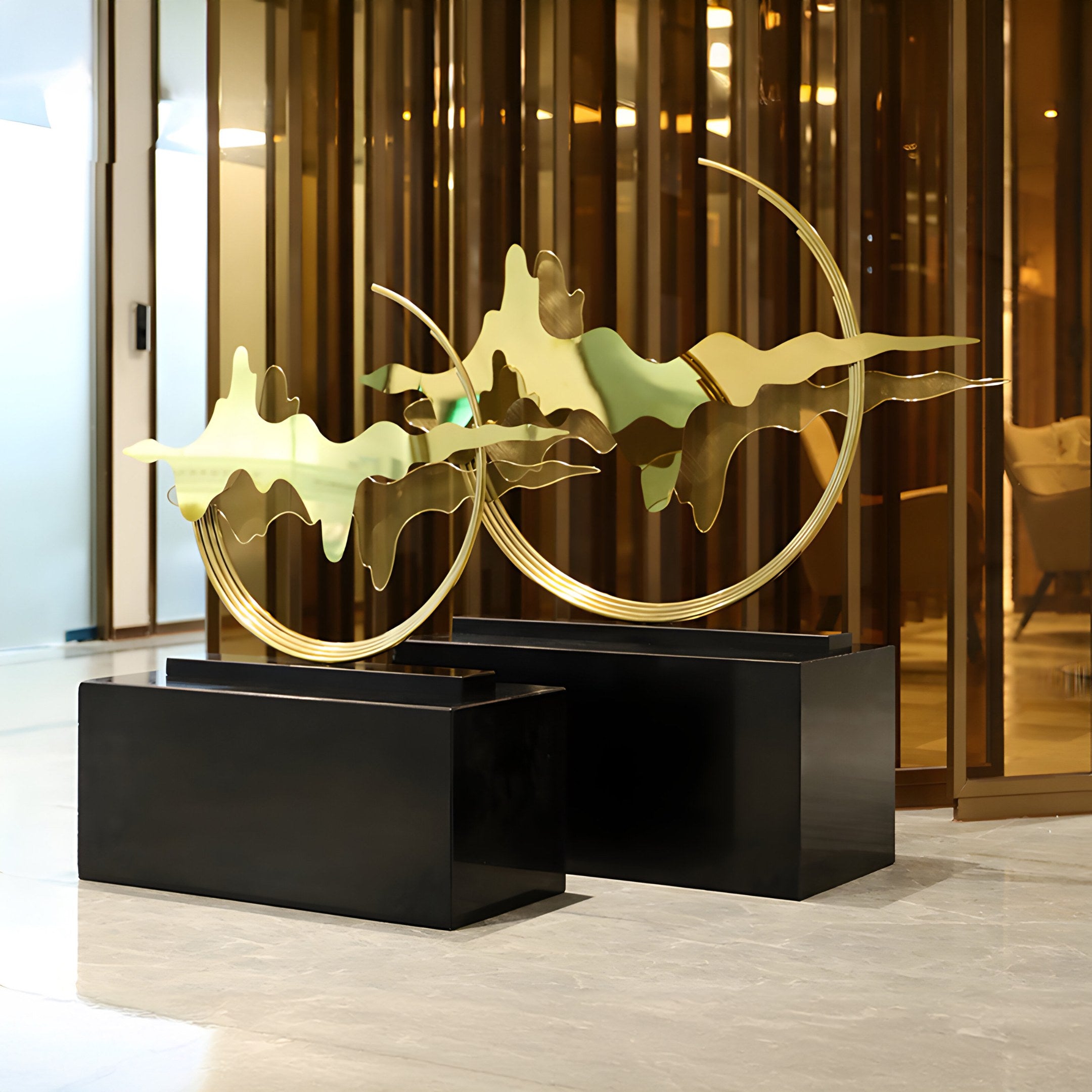 The Horizon Gold Abstract Sculpture is displayed in an upscale lobby, reflecting light off its polished surface.